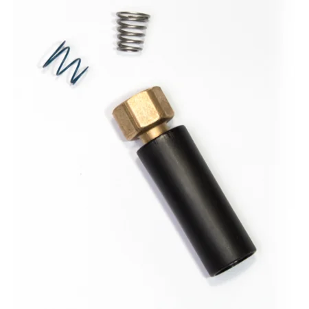 Schwarzer Kunststoffzylinder mit goldenem Messingkopf, daneben eine blaue Spiralfeder und eine silberne Feder auf weissem Hintergrund.
