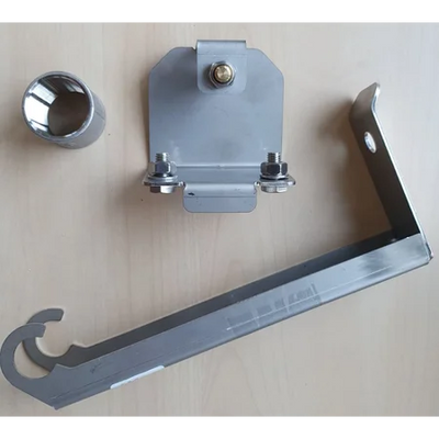 Stahl-Montagekit mit langem gebogenen Hakenarm, seitlicher U-/L-Halterung, runder Rohrhülse und zentraler Befestigungsplatte mit Bolzen – auf Holzfläche liegend.