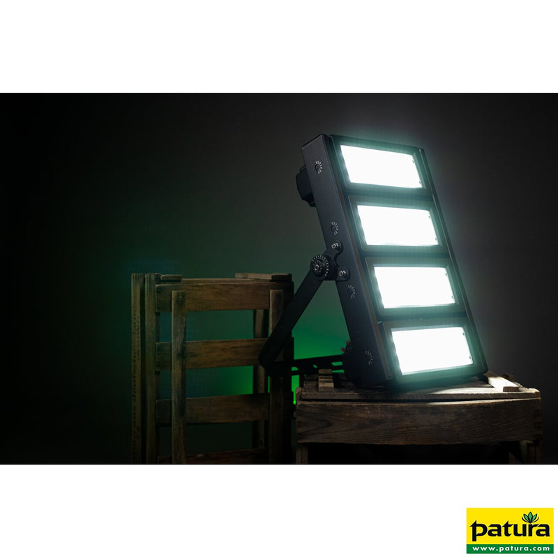 LED-Grow-Lichtpanel mit vier Leuchtflächen auf verstellbarem Arm, auf einer Holzkonstruktion vor dunklem Hintergrund; grünes Licht im Hintergrund, Patura-Logo unten rechts.
