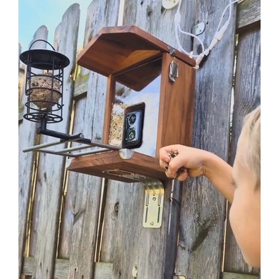 Vogelfutterhaus mit Kamera - Kind befüllt das Vogelfutterhaus mit Futter