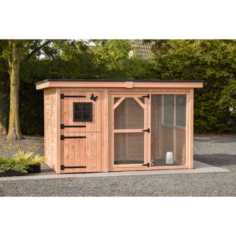 Holz-Hühnerstall mit Drahtgehege und kleiner schwarzer Fensterfront, robuste schwarze Türbeschläge; Wasserspender im Gehege, steht auf Kiesfläche im Garten und ist von Bäumen umgeben.