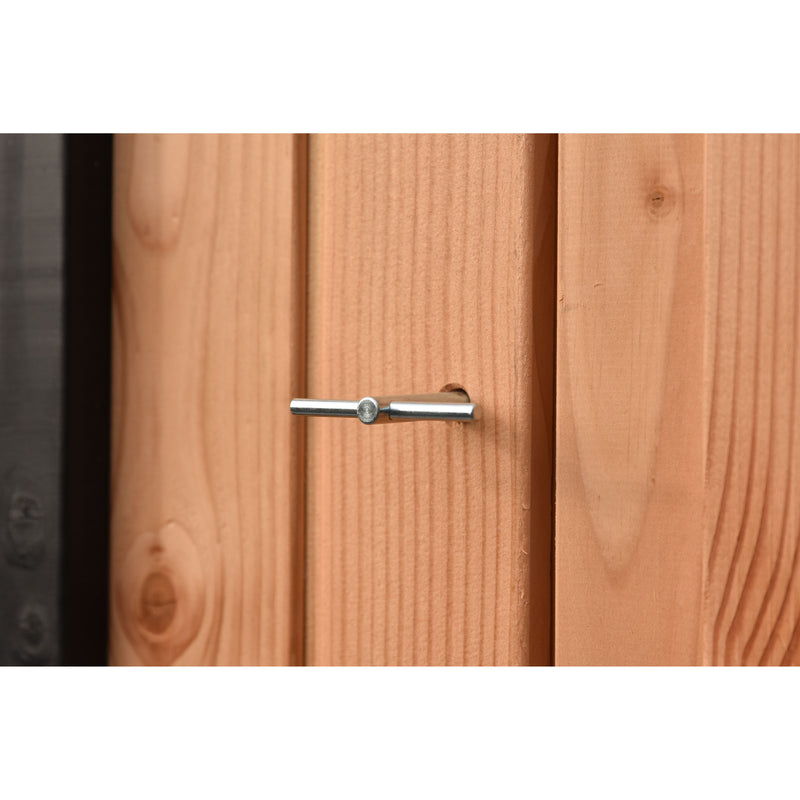 Nahaufnahme eines silbernen Türbolzens, horizontal durch ein Loch in einer hellbraunen Holztür gesteckt; sichtbare Holzmaserung und Türrand links.