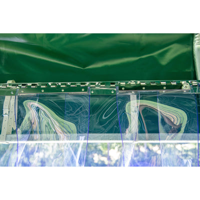 Detailansicht einer grünen Planenstruktur mit transparenten Kunststofffenstern, Metallleisten und Schraubverbindungen; reflektierende Oberflächen und draussen sichtbare Bäume.