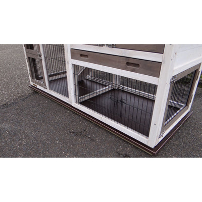 Kaninchenstall aus weissem Holz mit Drahtgitterwänden, steht auf Asphalt; offener unterer Bereich mit Metallboden.