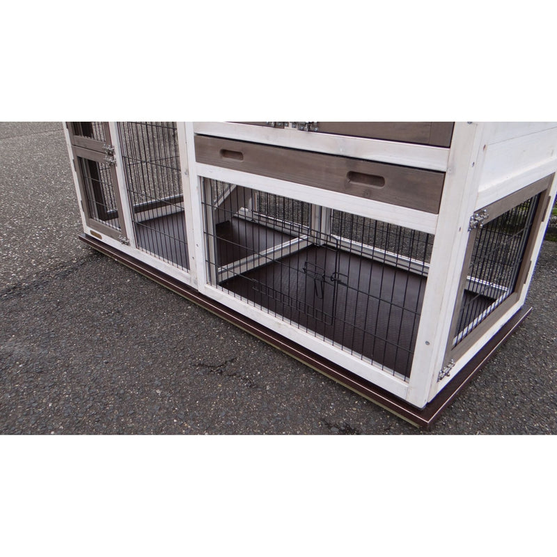 Kaninchenstall aus weissem Holz mit Drahtgitterwänden, steht auf Asphalt; offener unterer Bereich mit Metallboden.