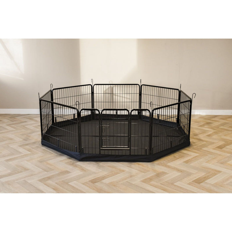 Schwarzes sechseckiges Metall-Haustierlaufgitter mit Tür, auf dunkler Bodenabdeckung, in hellem Wohnzimmer mit Parkettboden.