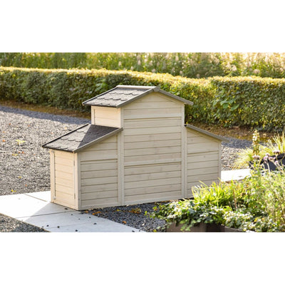 Gartenhaus aus Holz mit drei verbundenen Sektionen und grauen Schindeldächern, steht auf Kiesweg im Garten neben einer grünen Hecke.