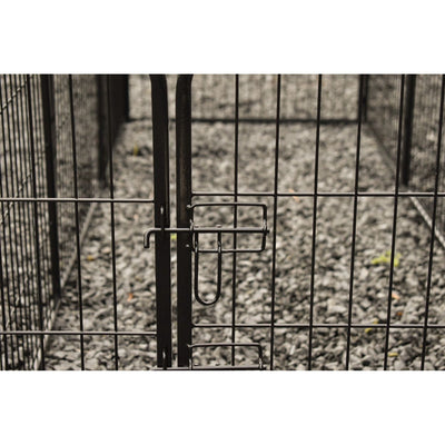 Nahaufnahme eines schwarzen Metallzauntors mit Verriegelung und Gittern, Kiesboden im Hintergrund.