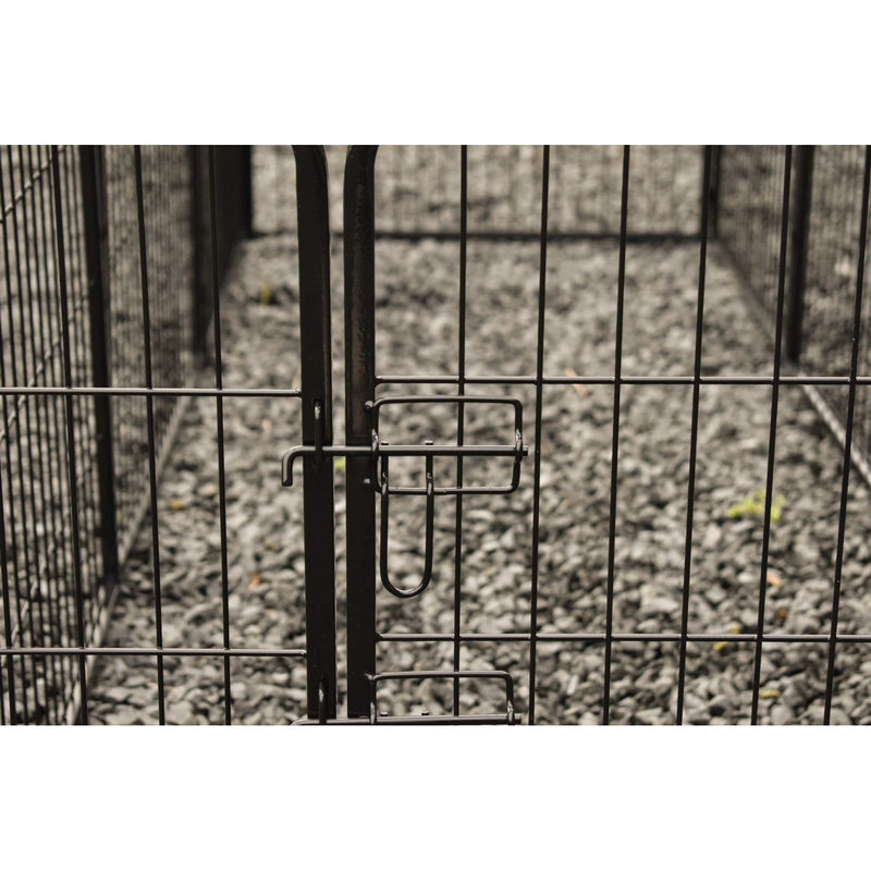 Nahaufnahme eines schwarzen Metallzauntors mit Verriegelung und Gittern, Kiesboden im Hintergrund.