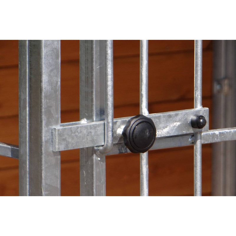 Nahaufnahme eines verzinkten Metallgitters mit Verriegelungsstange und schwarzer runder Verschlusskappe vor holzfarbenem Hintergrund.