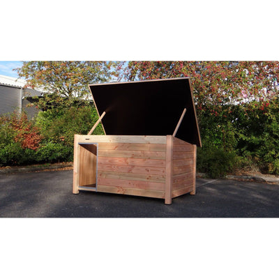 Offene Holzkiste als Garten-Aufbewahrungsbox aus Naturholz mit aufgeklapptem Deckel, umgeben von Bäumen und Sträuchern.