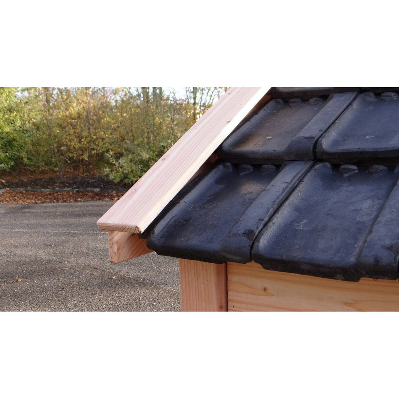 Nahaufnahme eines Holzdaches mit schwarzen Dachziegeln und sichtbarem Holzbalken; Hintergrund Herbstlaub und Parkplatz.