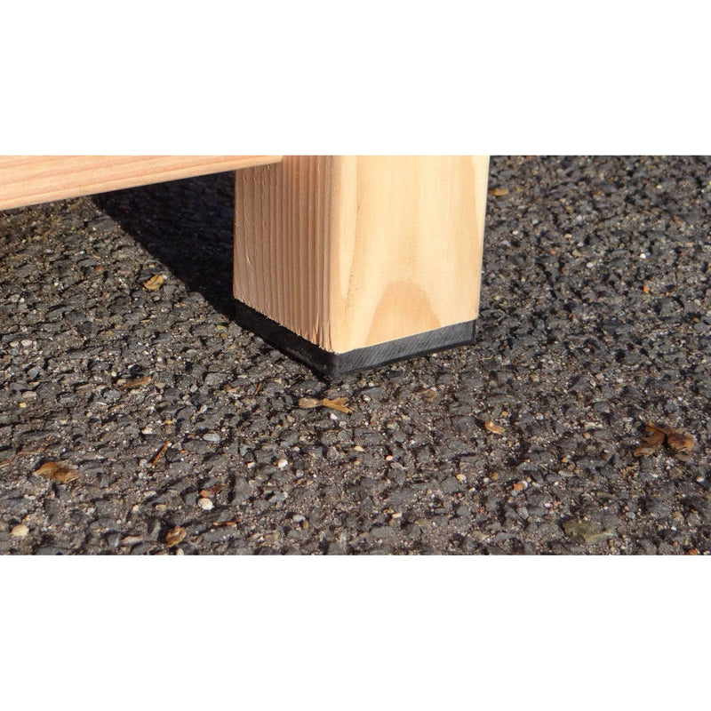 Nahaufnahme eines Holzmöbelbeins mit schwarzem Gummi-Fuss auf rauem Asphalt.