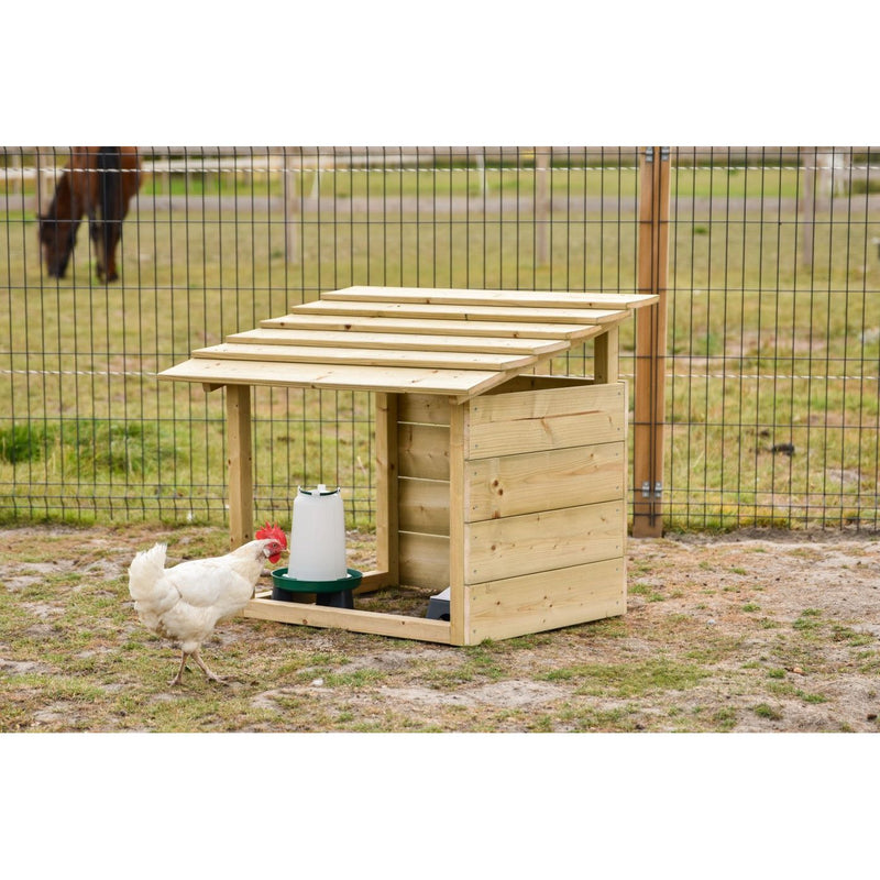 Holz-Hühnerstall mit schrägem Dach; davor ein weisses Huhn, Tränke und Futtertrog sichtbar, eingezäunter Aussenbereich im Hintergrund.