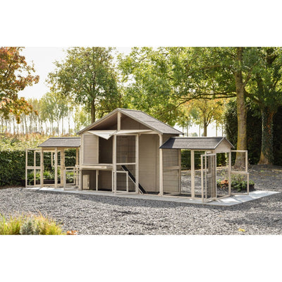 Grosser Holzhühnerstall mit Drahtgehege und Ausläufen in einem Garten auf Kiesboden, umgeben von Bäumen.