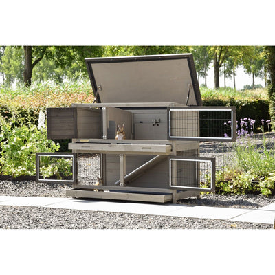 Grosser mehrstöckiger Kaninchenstall aus Holz mit Drahtgitter-Türen im Garten; zwei Kaninchen sitzen auf den Ebenen.