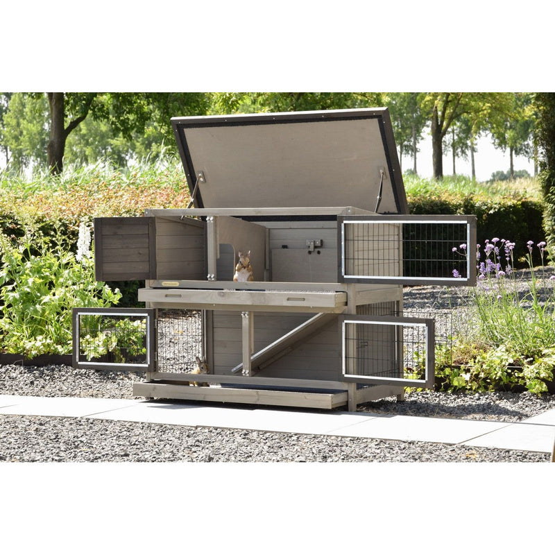 Grosser mehrstöckiger Kaninchenstall aus Holz mit Drahtgitter-Türen im Garten; zwei Kaninchen sitzen auf den Ebenen.