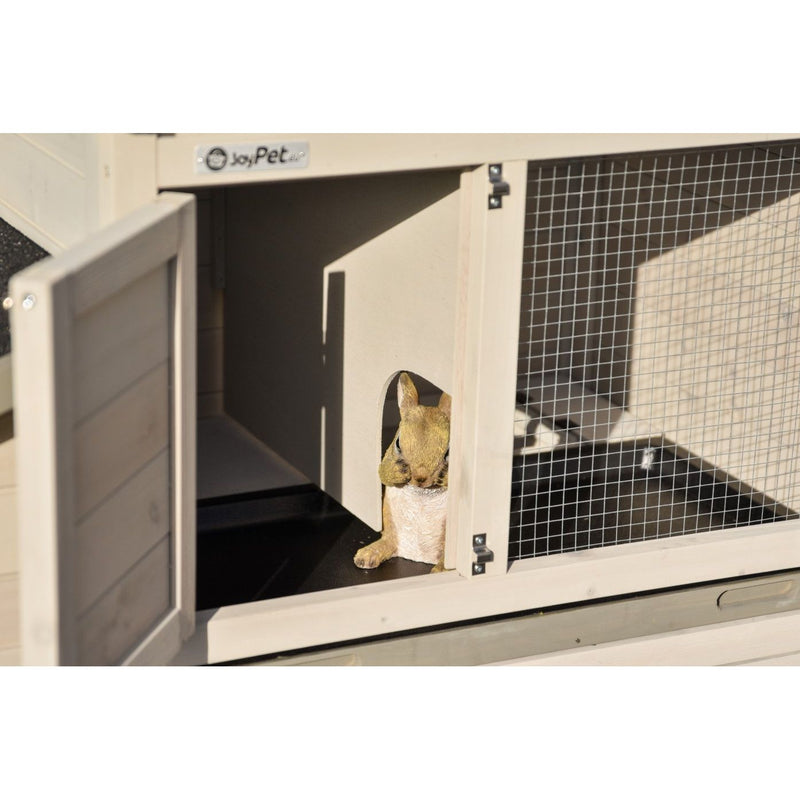 Kleines braunes Kaninchen schaut aus dem offenen Eingang eines Holz-Käfighauses mit Drahtgitter-Seite im Aussenbereich.