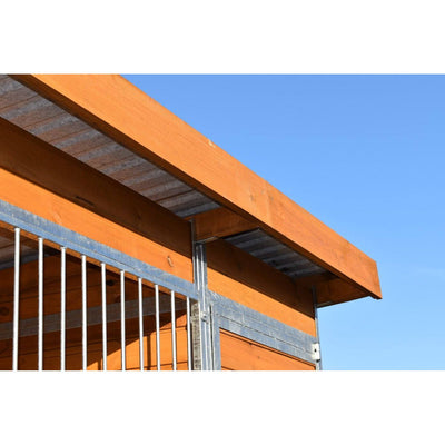 Nahaufnahme einer Holzbalkenkonstruktion mit Metallrahmen und vertikalen Metallstäben vor klarem blauen Himmel.