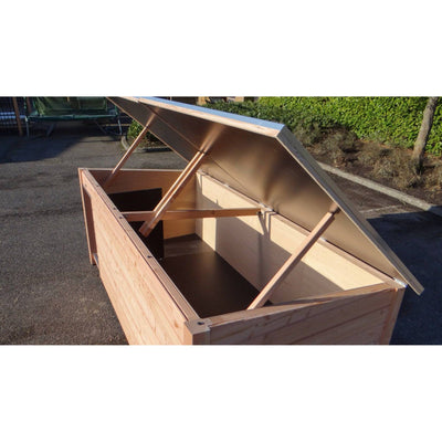 Grosse Holzkiste mit geöffnetem Deckel, von Stützstreben gehalten, Innenraum sichtbar, steht auf Asphalt im Freien.