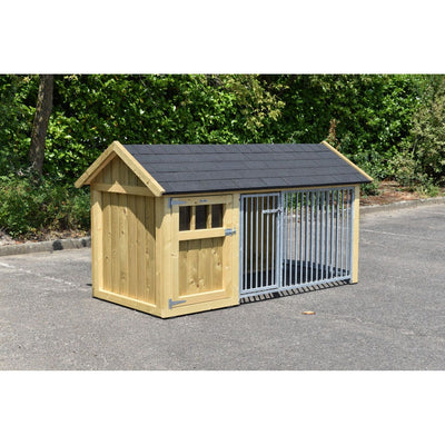 Holz-Hundehütte mit dunklem Schindeldach und angrenzendem Metall-Zwinger mit vertikalen Gitterstäben auf Asphalt vor grüner Hecke.