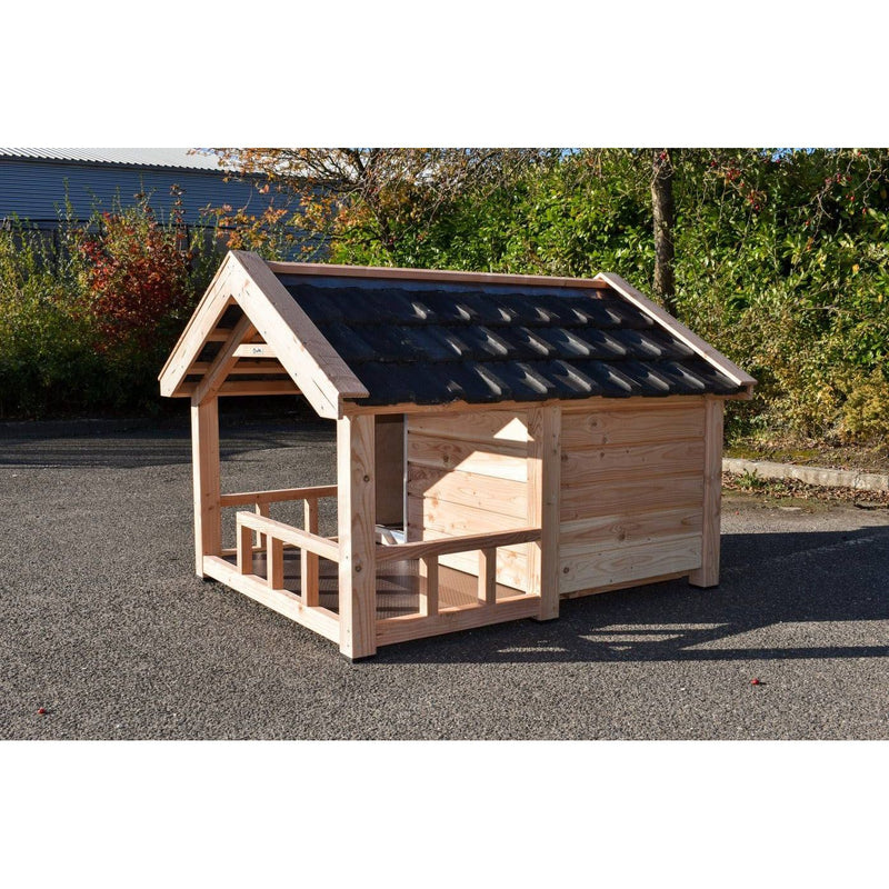 Holzspielhaus aus Naturholz mit offener Veranda, dunklem Dachziegel, steht auf Asphalt im Garten.