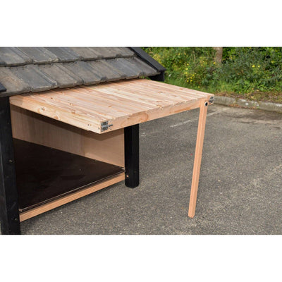 Ausklappbare Holztischplatte an der Seite eines Gartenhäuschens, unbehandeltes Holz, eine einzelne Holzstütze als Bein und Metallbeschläge.