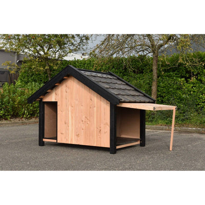 Holz-Hundehäuschen mit dunklem Dach und schwarzen Rahmen, naturfarbene Holzwand, offener Eingang; steht auf Asphalt vor einer grünen Hecke.