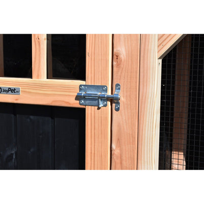 Nahaufnahme eines Holzgatters mit Metallriegelverschluss und JoyPet.eu-Aufkleber; Hintergrund aus dunklem Holz und Drahtgitter.