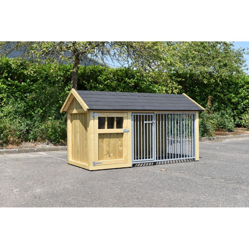 Holz-Hundehütte mit Satteldach und integriertem Metallgitterbereich, steht auf Asphalt vor grüner Hecke und Bäumen.