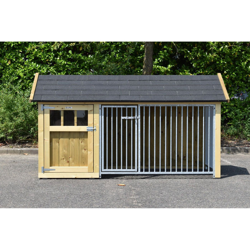 Hundehaus aus Holz mit links verschlossener Tür und rechts vergittertem Zwinger, dunkles Dach, steht auf einer Asphaltfläche vor einer grünen Hecke.