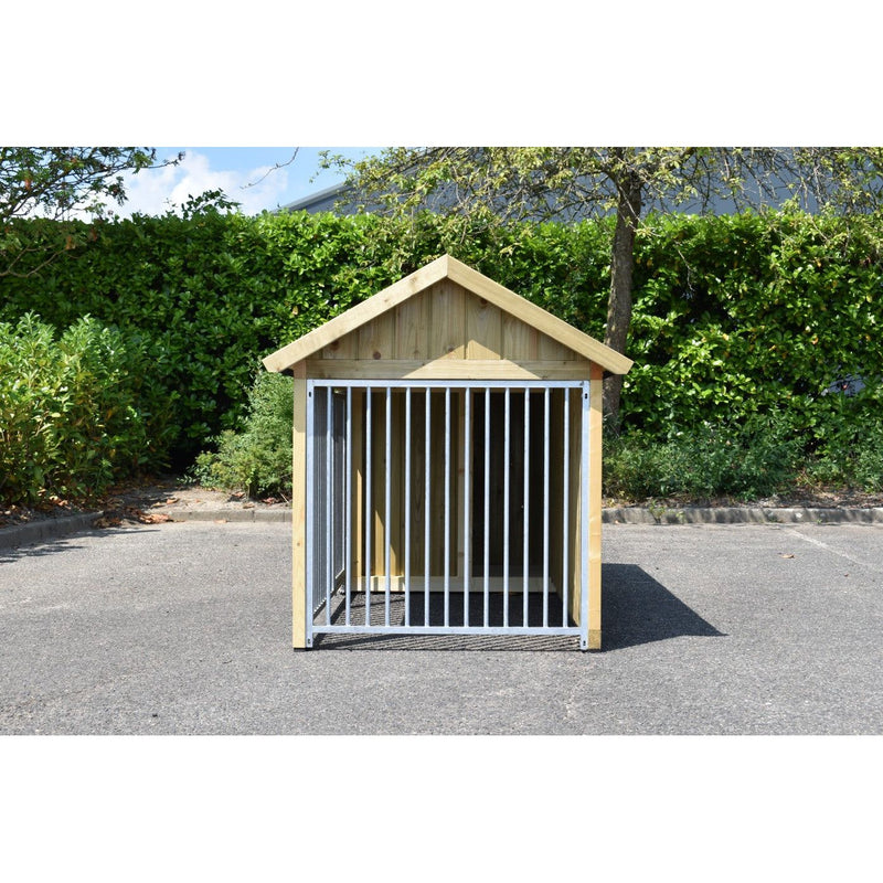 Holz-Hundehütte mit Tür aus vertikalen Metallstäben, steht auf Asphalt, grüne Hecke und Baum im Hintergrund.