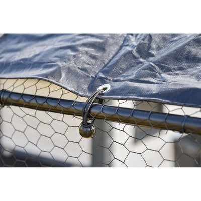 Nahaufnahme einer blauen Abdeckplane, die über einen Drahtgitterzaun gespannt ist, befestigt durch eine Metallöse und eine schwarze Bungee-Kordel mit einer kleinen schwarzen Kugel am Ende.