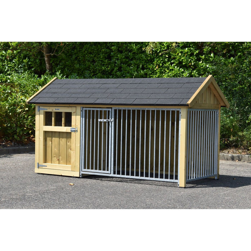 Hundehütte aus Holz mit integriertem Metallzwinger, links Holztür mit Fenster, rechte Seite aus Metallstäben, graues Schindeldach, Aussenbereich auf Asphalt vor grüner Hecke.