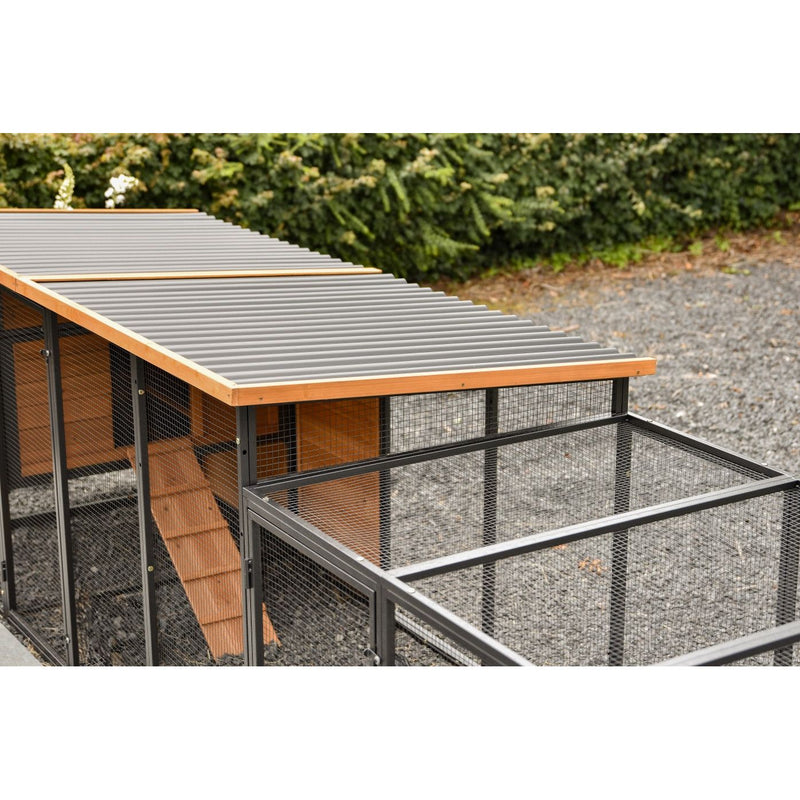 Hühnerstall mit Drahtgitterwänden, grauem Wellblechdach, Holzrahmen und Kiesboden im Garten.