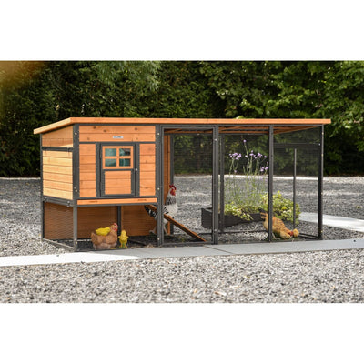 Holz-Hühnerstall mit Draht-Laufgehege auf Kiesboden; Hühner und Küken im Gehege, grüne Bäume im Hintergrund.