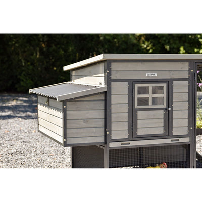 Grauer Holzhühnerstall mit seitlicher Nestbox, Fronttür mit Fenstergitter und Netzboden im Garten