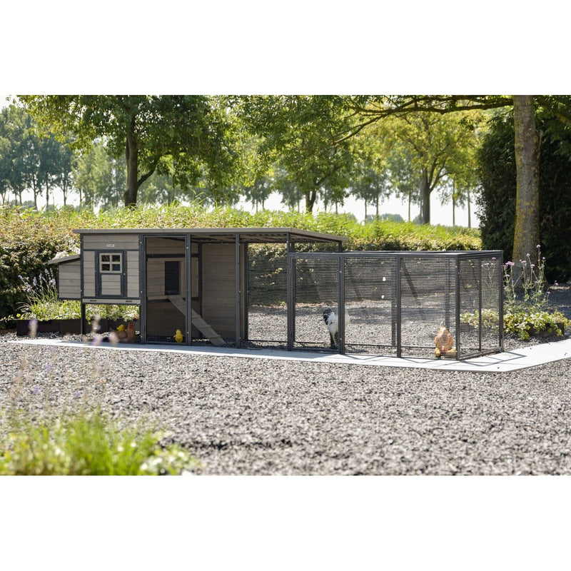 Hühnerstall mit angeschlossenem Drahtgitter-Auslauf im Garten, Kiesboden, umgeben von Bäumen; Hühner im Gehege.