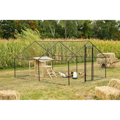 Offenes Hühnergehege aus schwarzem Metallrahmen mit Holzhäuschen und Leiter, Hühnern im Gehege, auf einer Wiese neben einem Maisfeld mit Heuballen im Hintergrund.