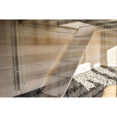 Holztreppe mit Stufen als Rampe lehnt diagonal an der Holzfassade eines Garten-Schuppens; Kiesboden im Vordergrund.