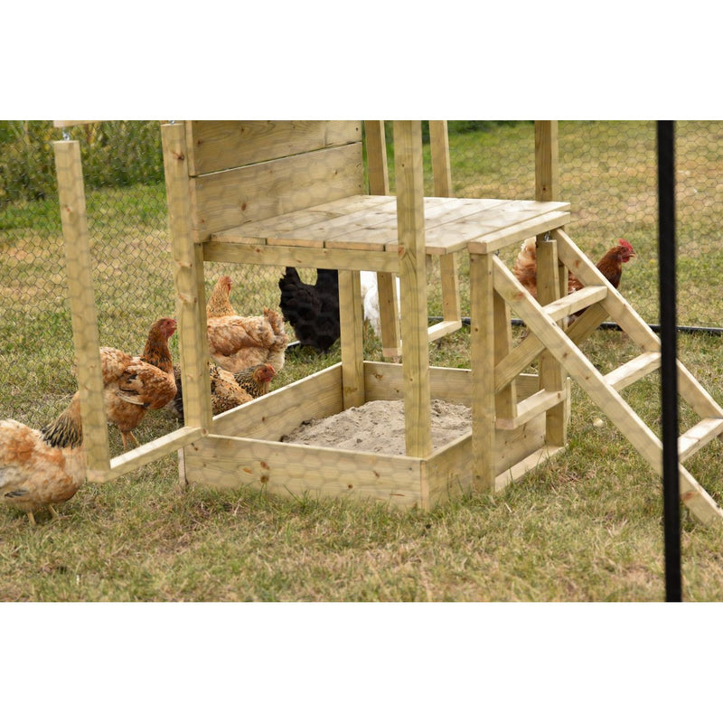Holz-Hühnerstall mit Rampe und Sandkasten im Freien, von Drahtzaun umgeben; braune und schwarze Hühner laufen auf der grasigen Wiese.