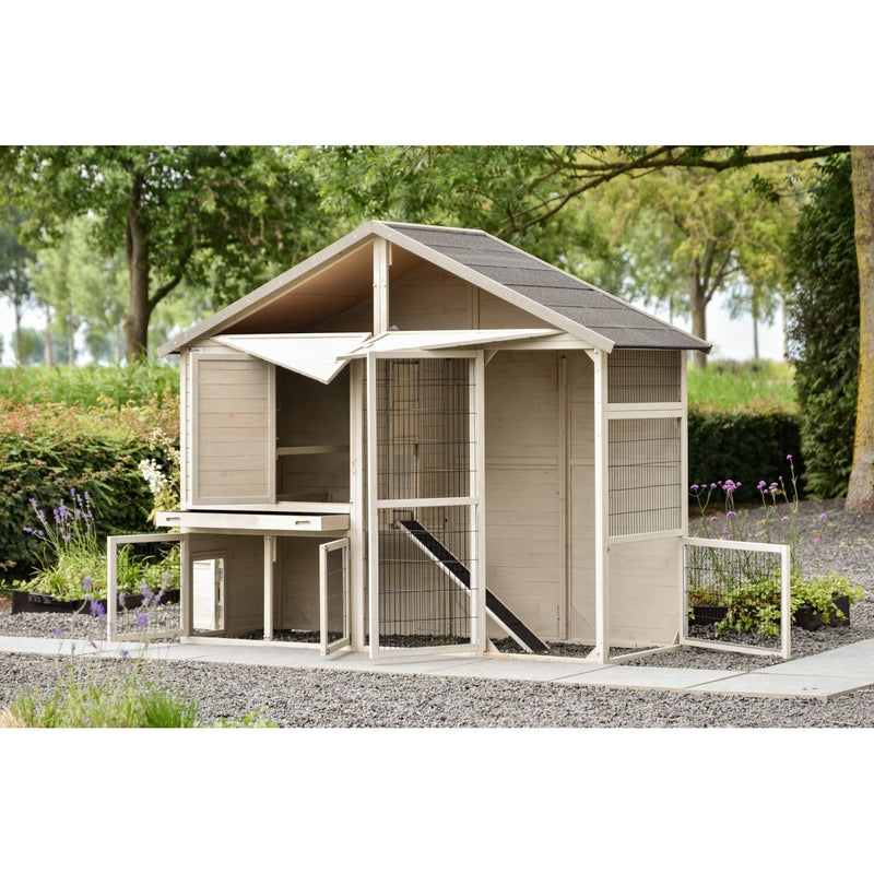 Holz-Hühnerstall mit Drahtgehege und Rampe im Garten auf Kies, umgeben von Bäumen und Blumen.