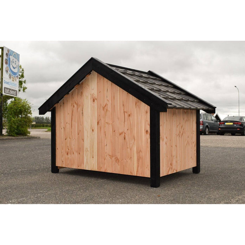 Kleines Gartenhaus aus Naturholz mit dunklem Dach und schwarzem Rahmen, steht auf einem asphaltierten Parkplatz; im Hintergrund geparkte Autos und eine Werbetafel.