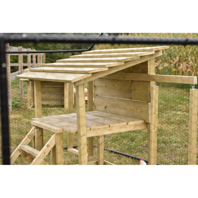 Holz-Hühnerstall im Garten, erhöht auf Pfosten, mit schrägem Latten-Dach, Rampe und Drahtzaun im Hintergrund; ein Huhn steht davor.