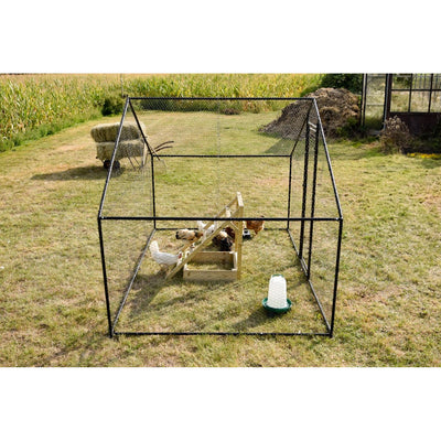 Aussenhühnerstall aus Drahtgitter im Garten, rechteckiger Hühnerlauf mit mehreren Hühnern, Holzfuttertrog und grüne Tränke auf Gras; Heuhaufen im Hintergrund.