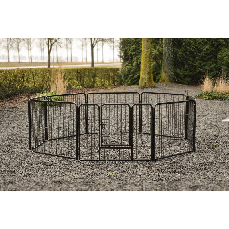 Schwarzes, modular aufgebautes Hundegitter aus Metall in kreisförmiger Anlage mit zentraler Tür, auf Kiesboden im Garten.